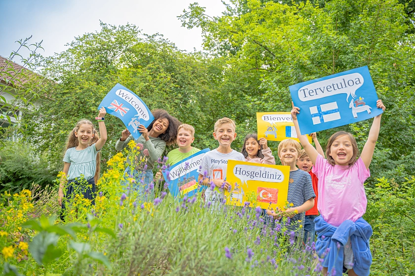 Bild von Kindern mit Schildern in verschiedenen Sprachen